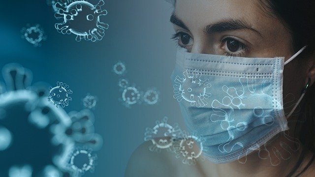 image of a woman in a surgical face mask, surrounded by viruses