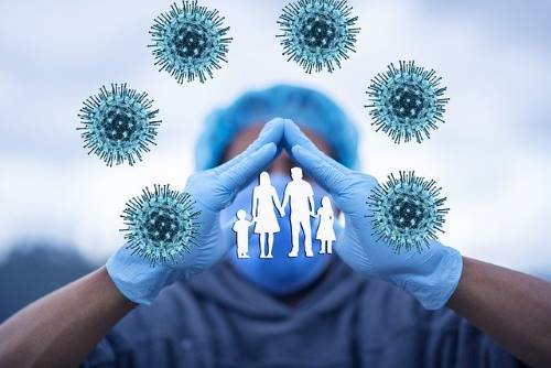 Covid cells on a blue background with hands providing a shield over 3 human figures