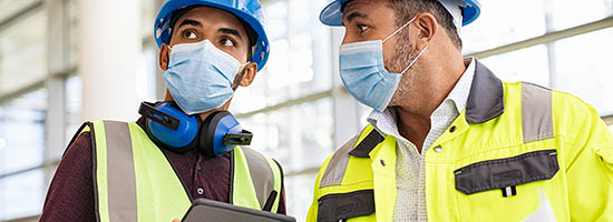 Architect and technician at a construction site reviewing blueprints.