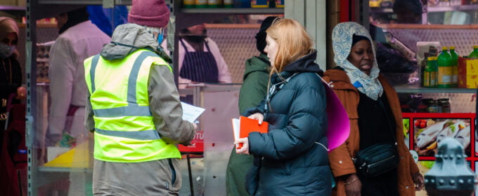 Image of people conducting a survey in front of a shop selling food.