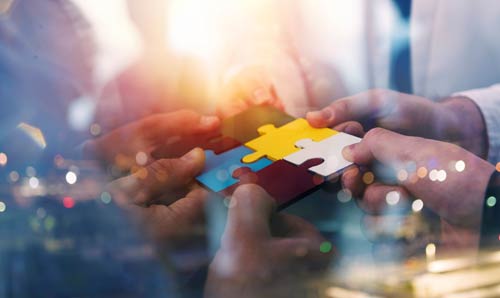 Business people joining puzzle pieces in an office setting, symbolising teamwork, problem-solving, and collaboration in a professional environment