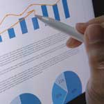 Close up of a pen drawing a line through a report's bar chart